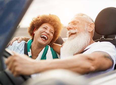 joyful senior couple riding in their convertible