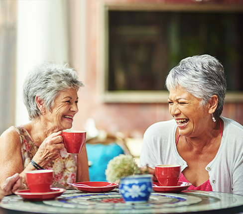 girlf friends laughing while drinking tea at an outdoor cafe